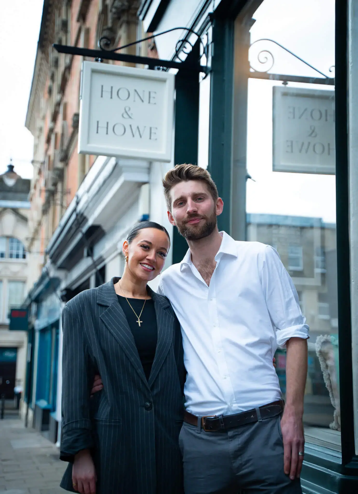 Sam & Gigi standing together with the shop front sign behind them
